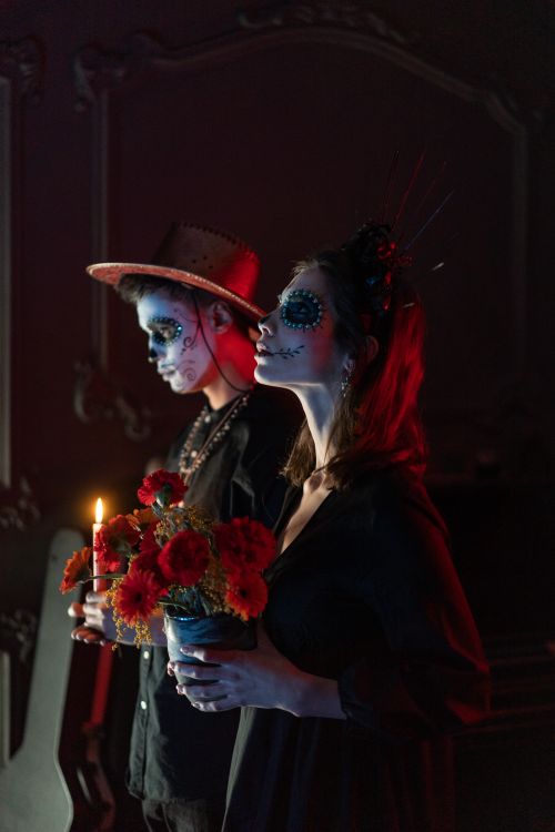 Free Two adults with face makeup holding flowers and candle for Day of the Dead. Stock Photo