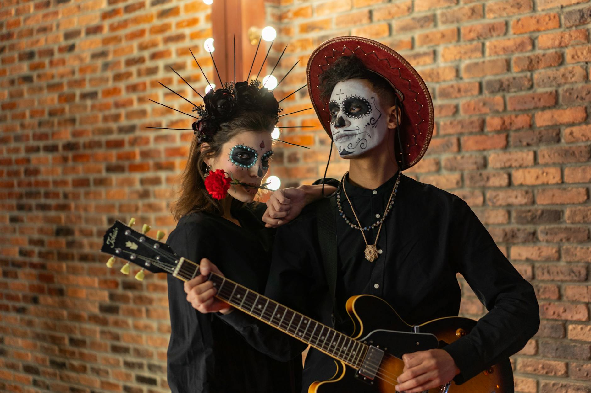 Artistic couple in Day of the Dead attire posing with guitar and makeup.