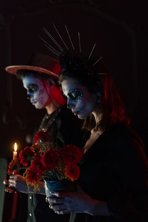 Free Two people with face paint during Dia de los Muertos, holding flowers and candles. Stock Photo