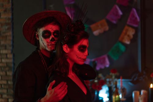 Free A couple in Día de los Muertos attire and face paint poses with candles and decorations. Stock Photo