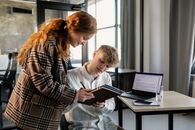 Man and Woman Sitting on Chair While Reading Book