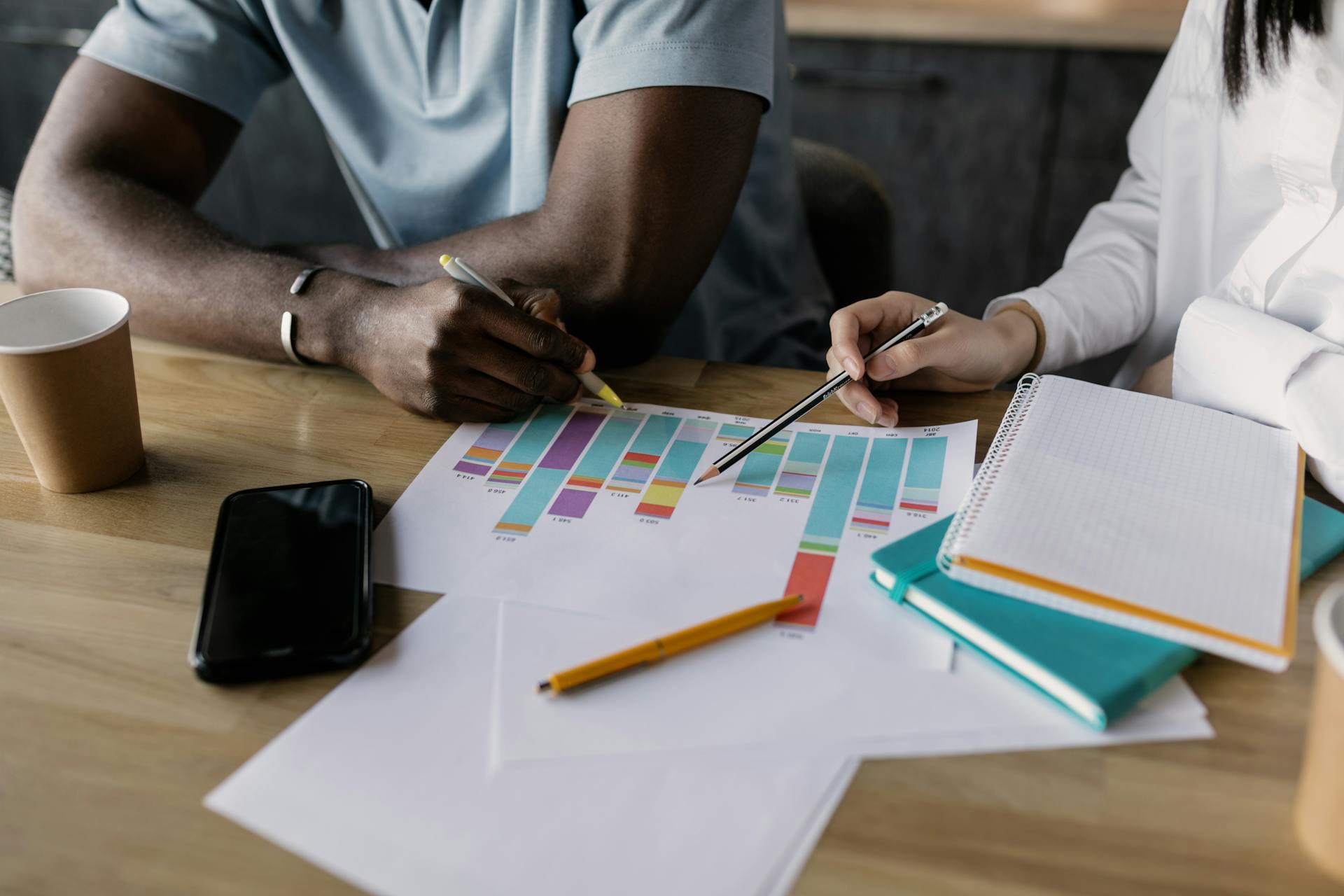 Two professionals planning business strategy using graphs and papers.