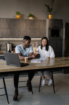 Two colleagues collaborating at a table in a modern office setting with a friendly, productive atmosphere.