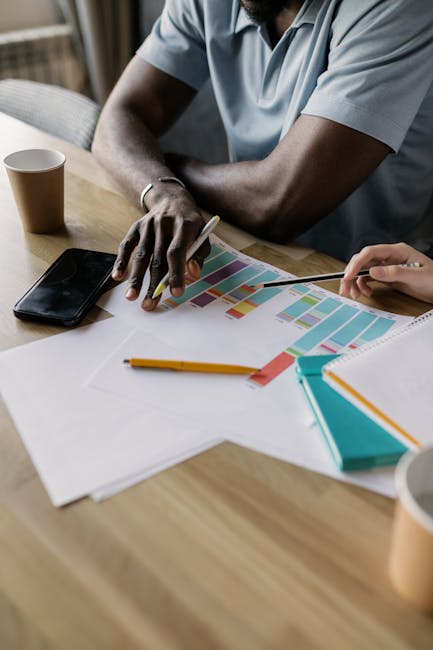 Deux professionnels collaborent sur un plan de projet coloré.