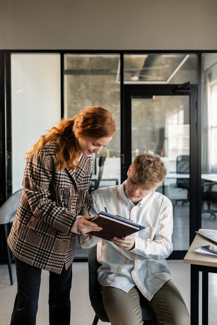 A Woman Having Her Colleague Sign A Document