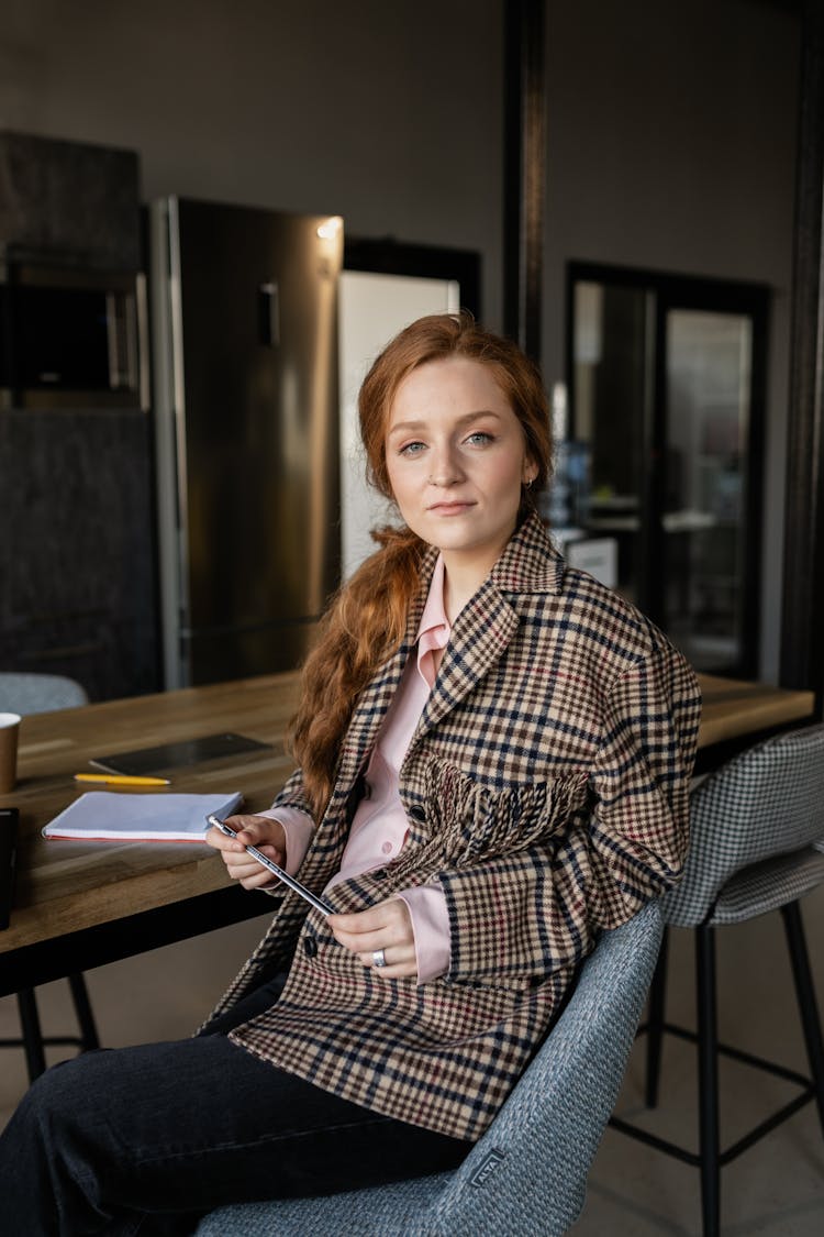 Redhead Woman In Checkered Coat Sitting On Chair