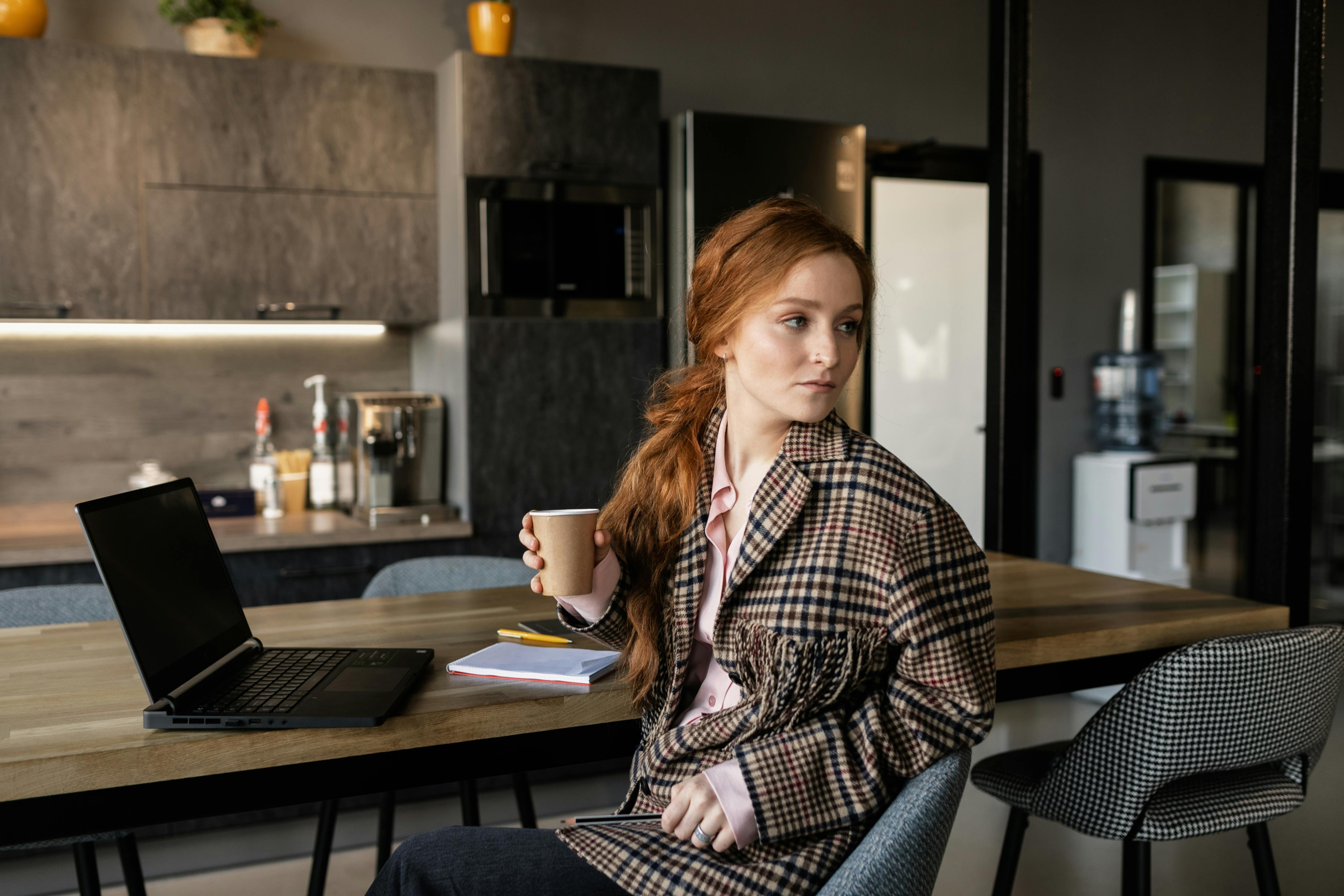 busy professional in Ho working at a laptop with a cup of coffee, looking tired but determined