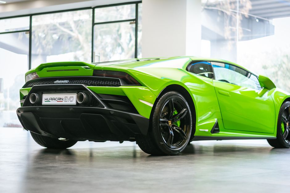 Sleek green Lamborghini Huracan EVO showcased in a modern indoor showroom setting.