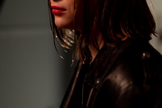Close-up portrait of woman with red lips and wet hair wearing a black leather jacket.