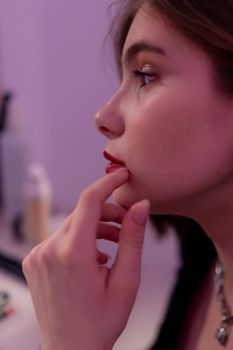 Profile shot of a woman with chin resting on hand, contemplating indoors.