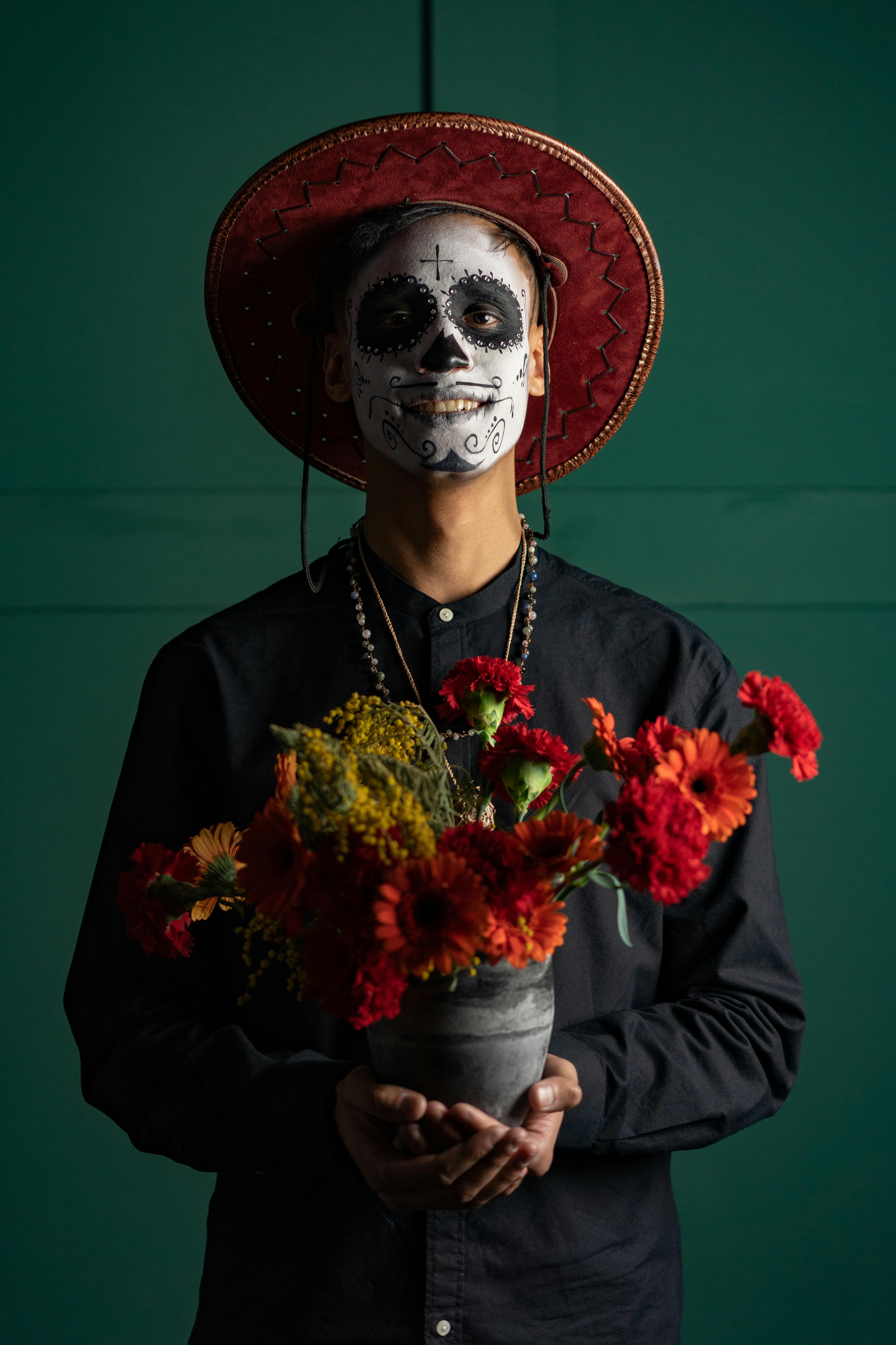 a man with face paint holding a pot of flowers