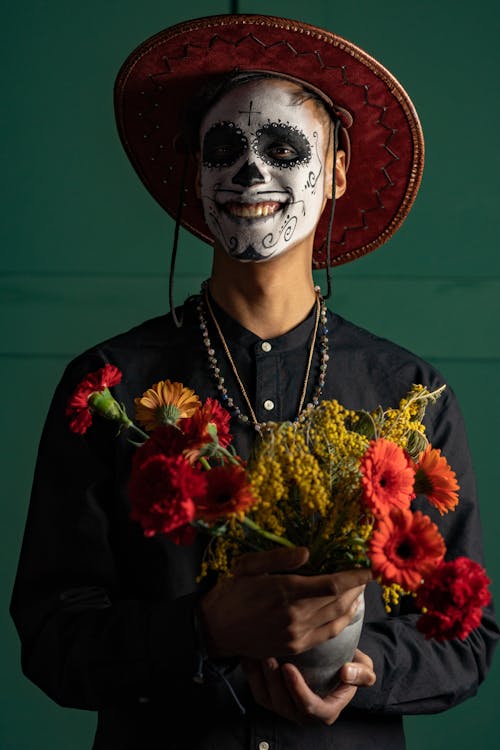 A Man with Face Paint Holding a Pot of Flowers
