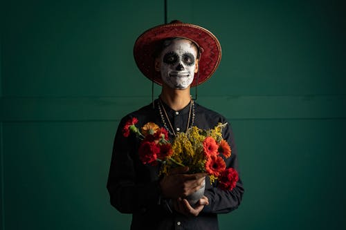A Man with Face Paint Holding a Pot of Flowers