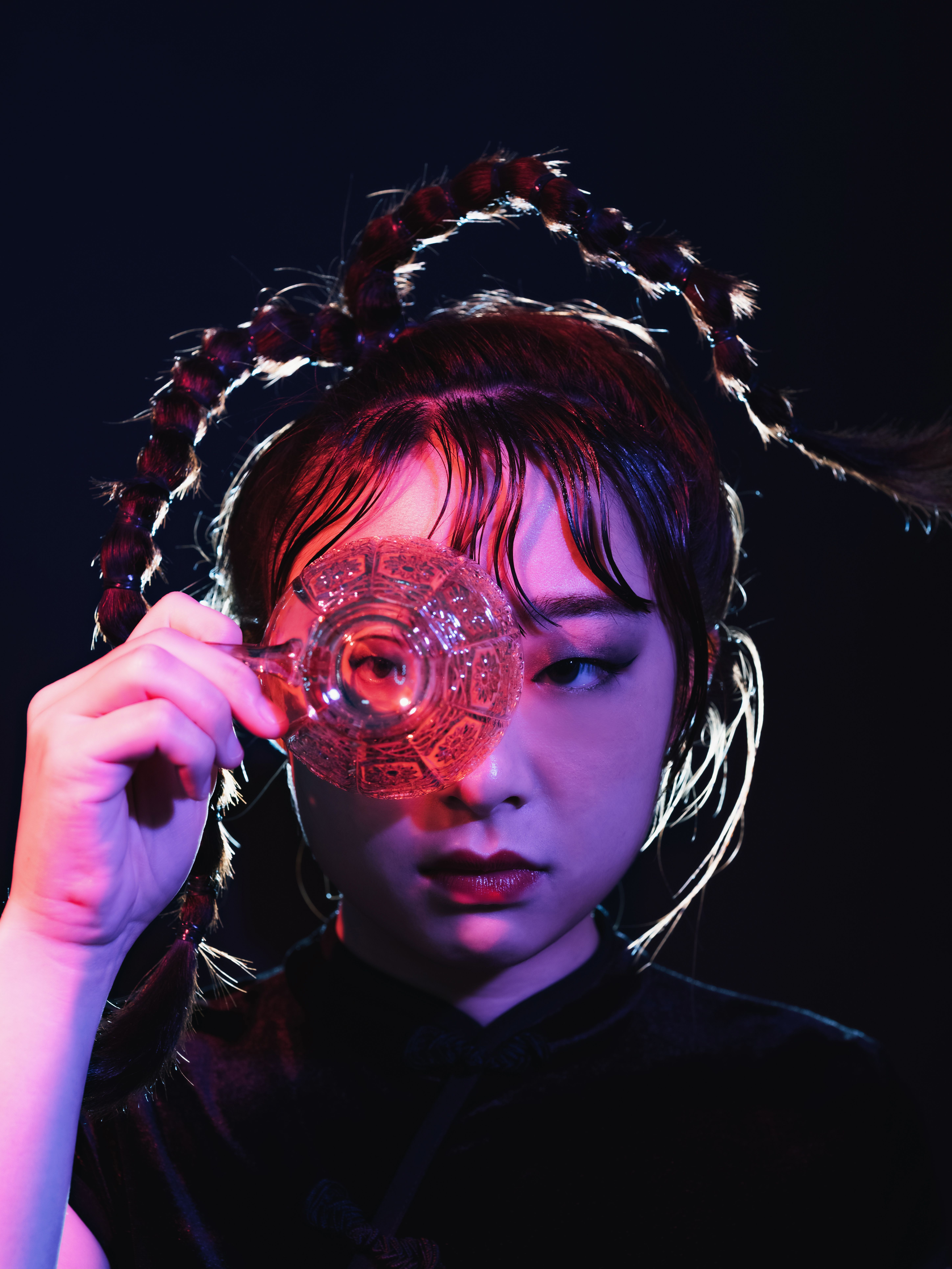 Creative portrait of a woman holding a glass object in vibrant lighting.