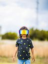 Little kid in t shirt and polarized protective mask standing on blurred background of field