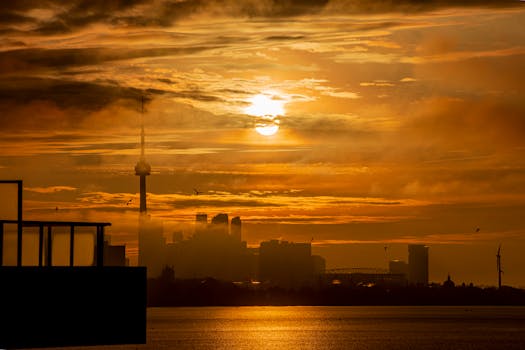 Captivating sunrise over Toronto's skyline featuring the iconic CN Tower and shimmering golden waters.
