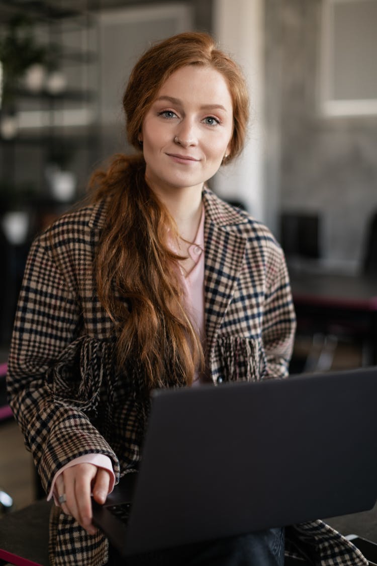 Portrait Of A Woman With Red Hair Holding A Laptop