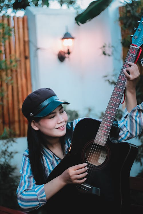 Kostnadsfri bild av akustisk gitarr, asiatisk kvinna, keps