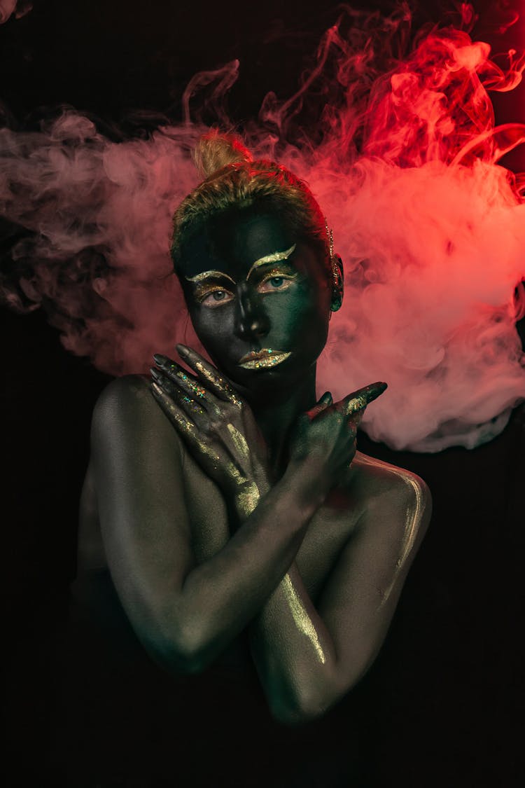 Woman With Black Paint On Body And Face And Golden Makeup