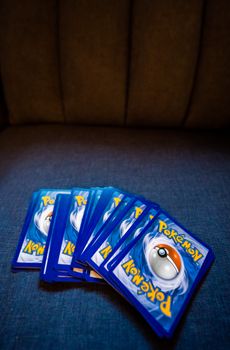 Collection of Pokemon trading cards fanned out on a sofa. Ideal for gaming and collectibles imagery.