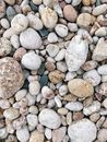 From above of stack of stones of various shapes and colors scattered on rocky beach on sunny day