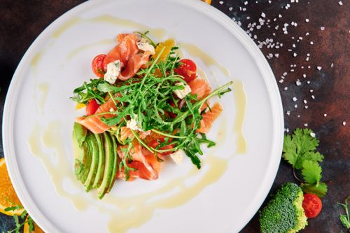 Free A top-view shot of a vibrant salmon and avocado salad with arugula, cherry tomatoes, and feta cheese. Stock Photo