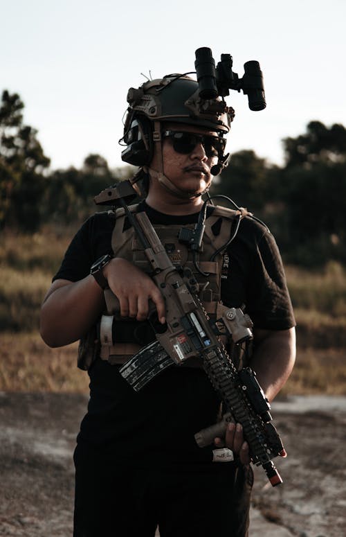 

A Man Wearing Combat Attire Holding a Rifle