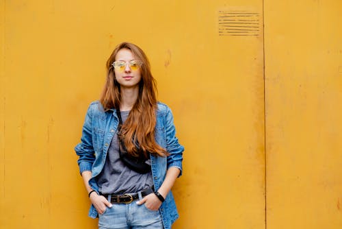 Free A Woman Standing In Front of a Yellow Wall Stock Photo