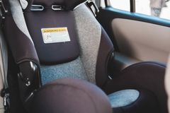 Travel car seat for babies placed on passenger seat of contemporary automobile with magazines near window parked on street of city