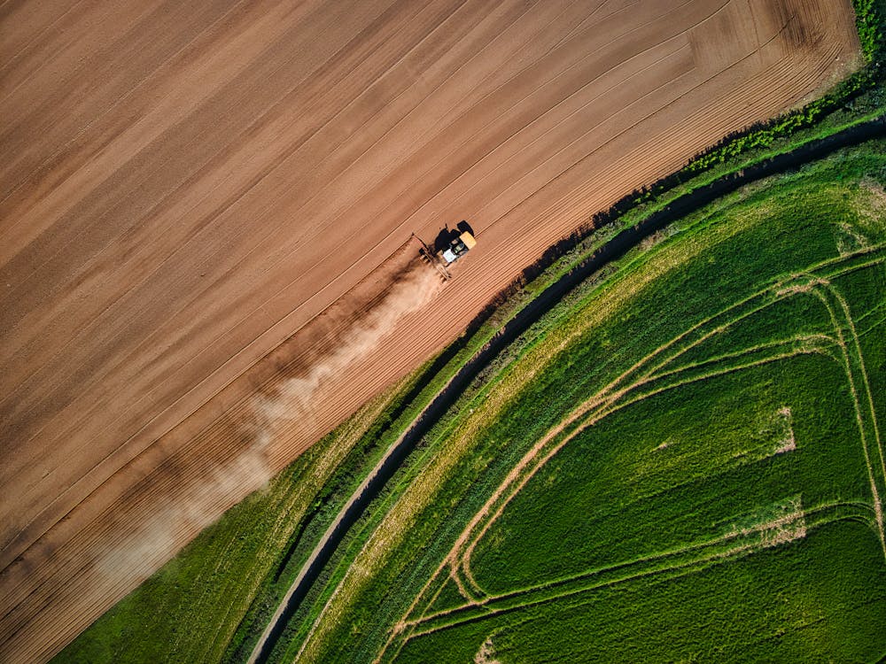 Free Drone Shot of a Tractor on a Field Stock Photo