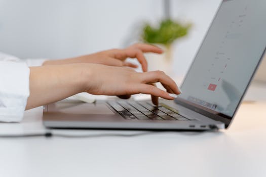 Hands typing on a laptop keyboard, ideal for concepts of remote work and technology.