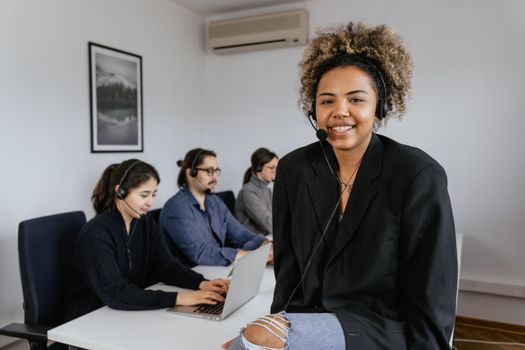Group of diverse adult professionals working remotely in an office, communicating over headsets.