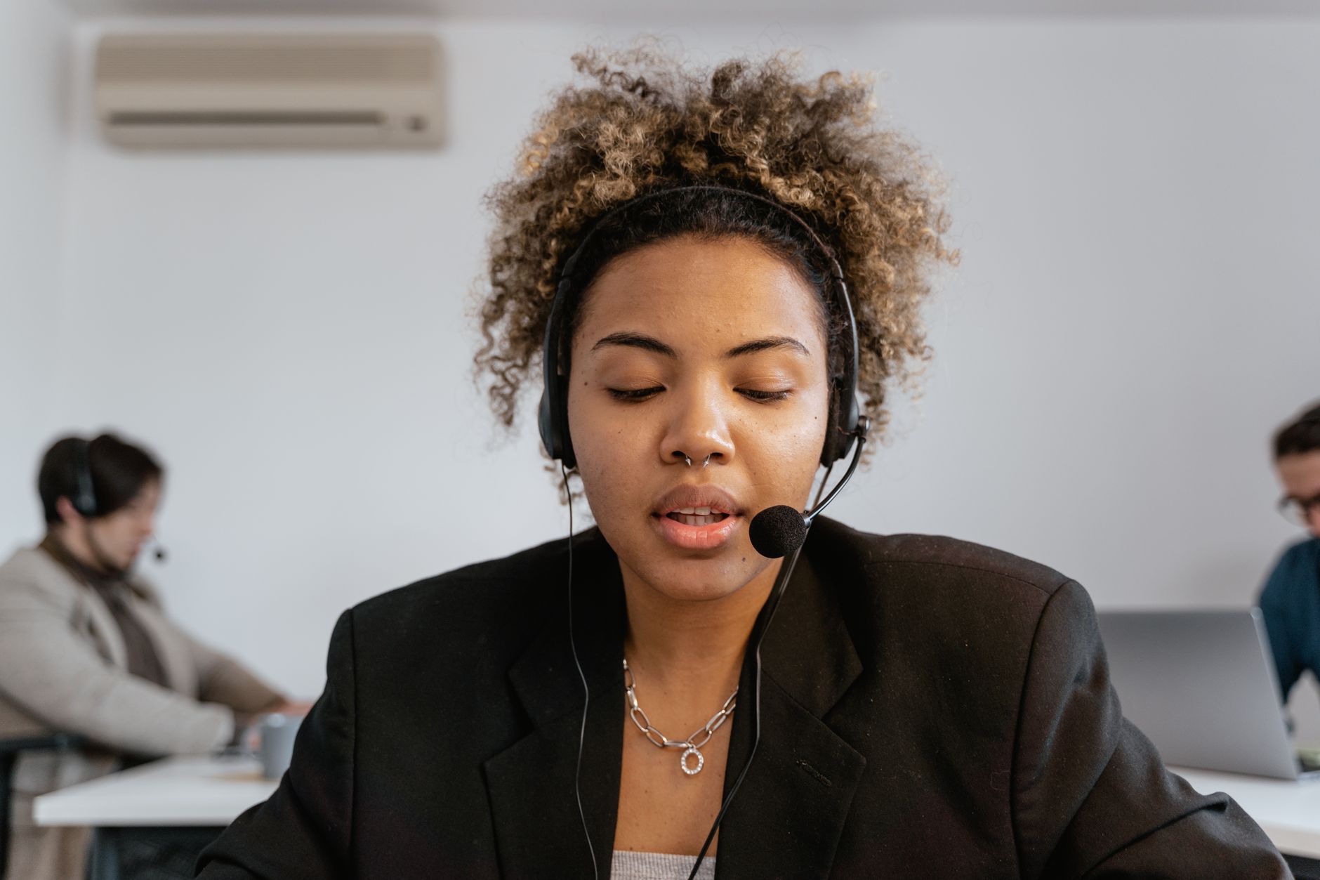 Focused customer support agent with headset, working in an office environment.