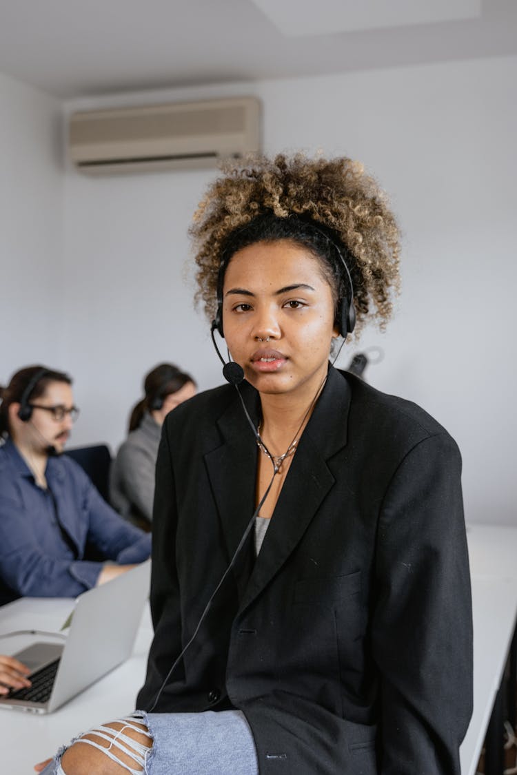 A Woman Wearing A Black Blazer And A Black Headset