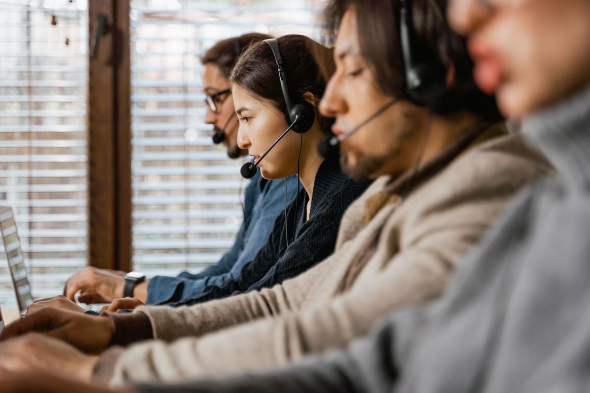 Masada akıllı telefon tutan eller ve kulaklıklı müşteri temsilcisi