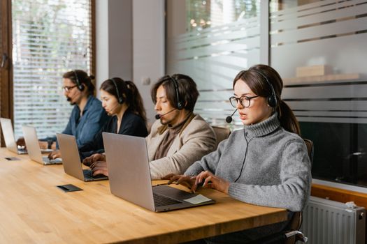 Call center team working at laptops with headsets, providing customer support.
