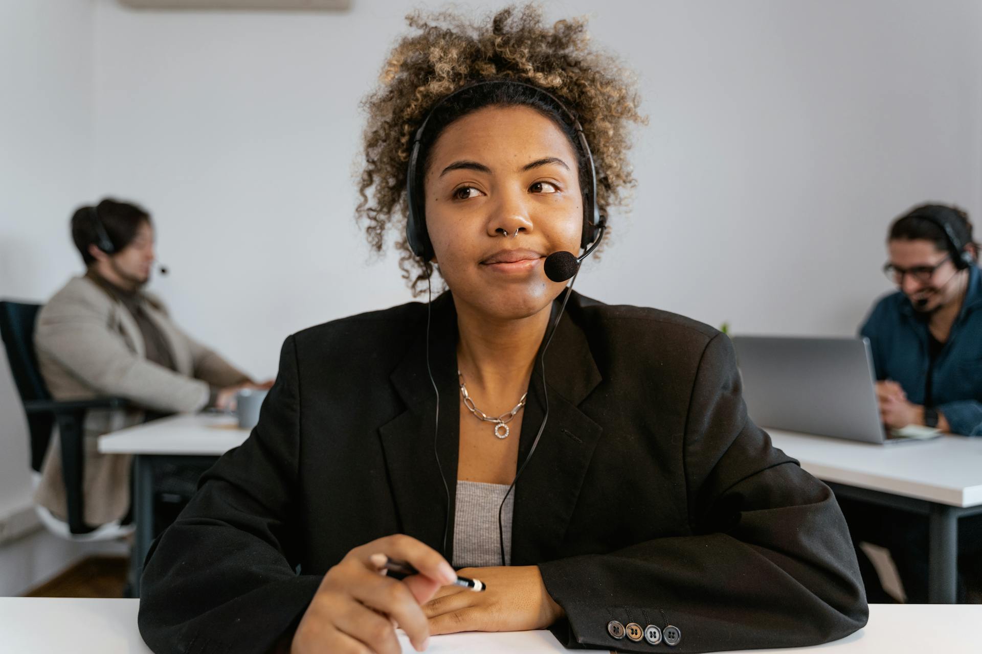 Close-up of a customer service agent in a corporate office wearing headphones and smiling.