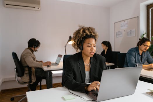 Professional team members with headsets working at laptops in a modern office setting.