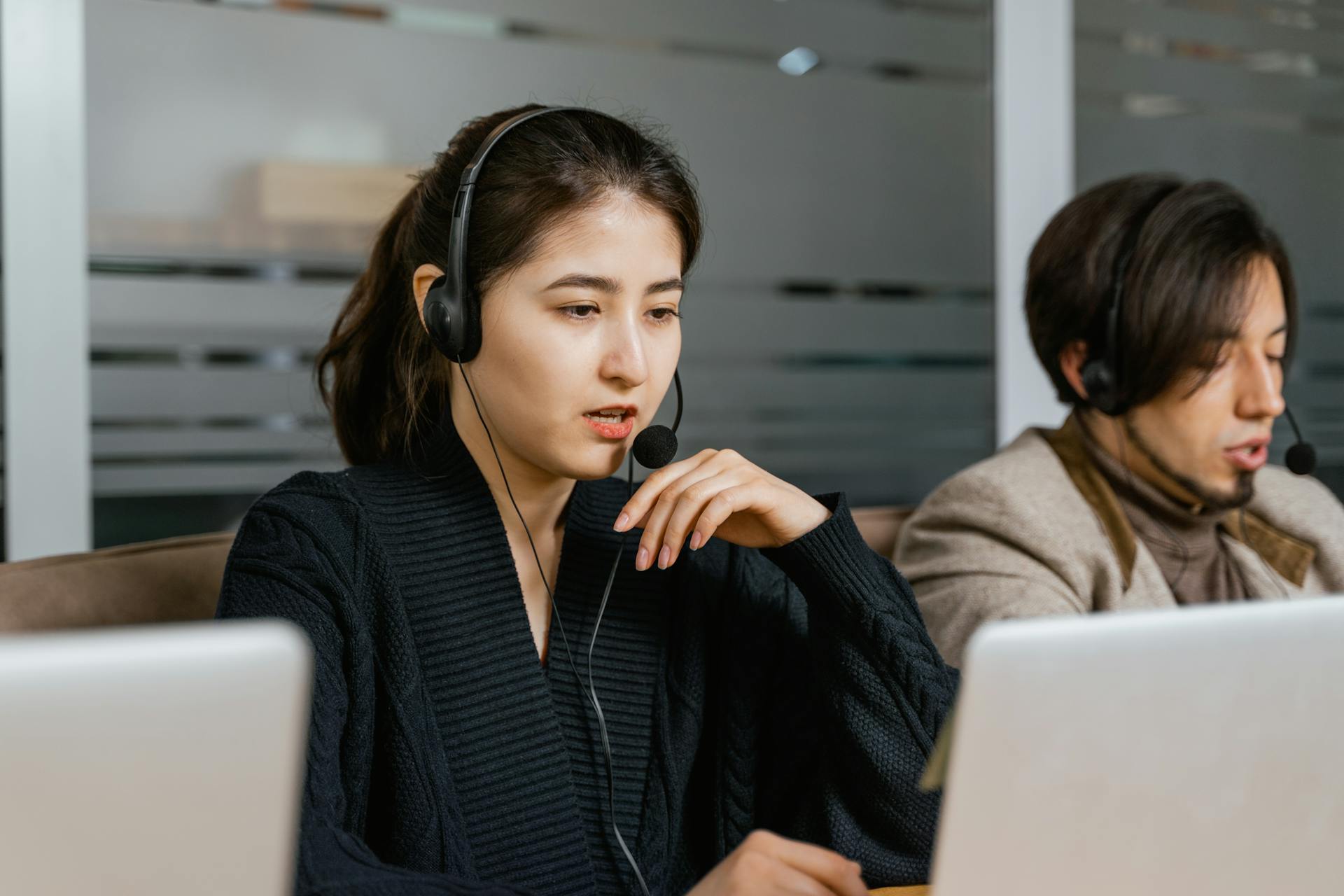 Two call center agents providing customer support in a modern office setting.