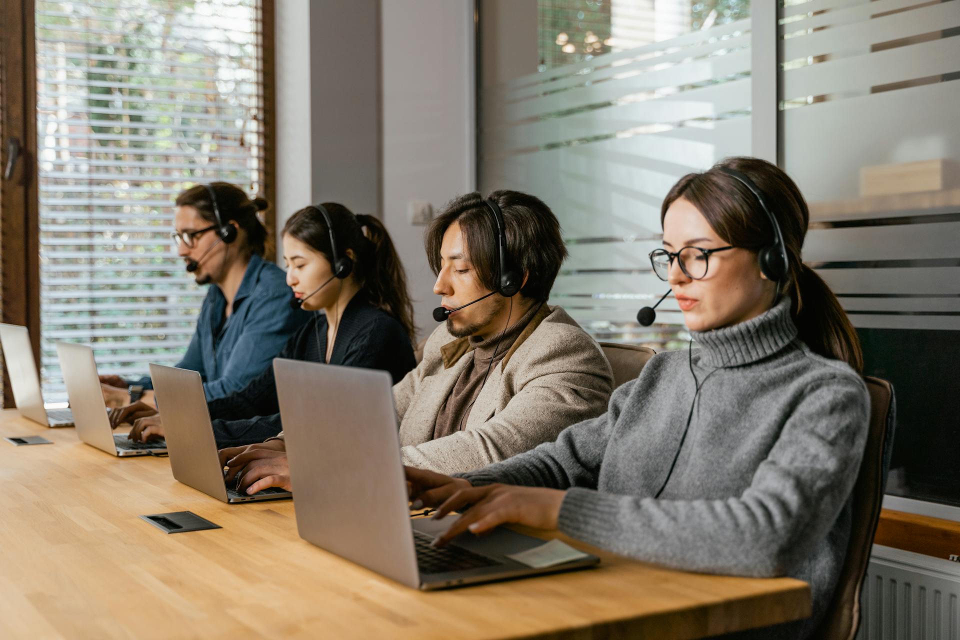 A diverse call center team uses laptops and headsets to provide customer support efficiently.