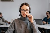 Photo of a Woman with Black Framed Eyeglasses Touching a Microphone