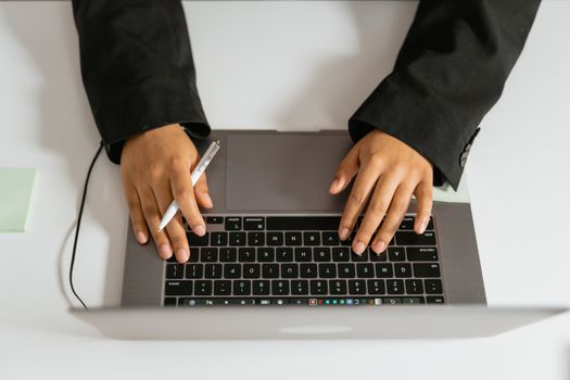 A businessperson working on a laptop with a pen for multitasking efficiency.