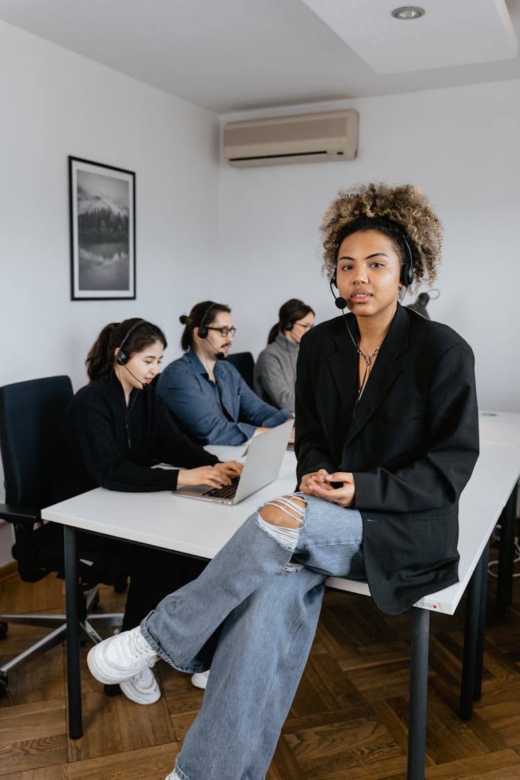 Photo Of A Woman With Curly Hair Sitting Near Her Coworkers