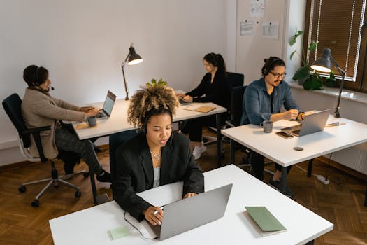 Diverse team of call center agents working at computers in an office setting, focused on tasks.