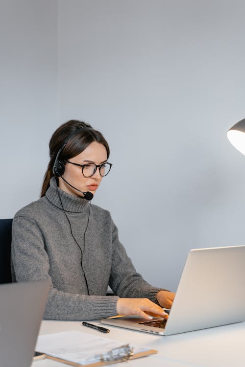 Woman in a Gray Sweater Typing on Her Laptop