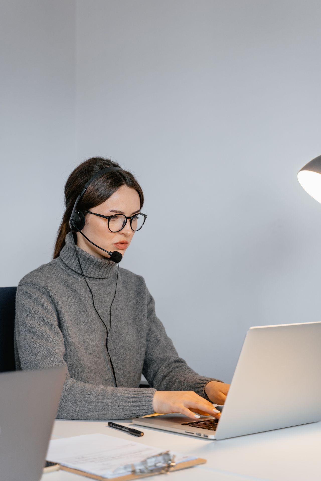 Focused woman in office with headset, providing customer support on laptop