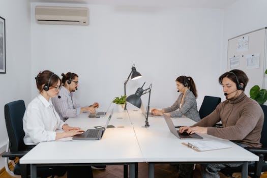 A diverse group of professionals working on laptops in a modern call center office.