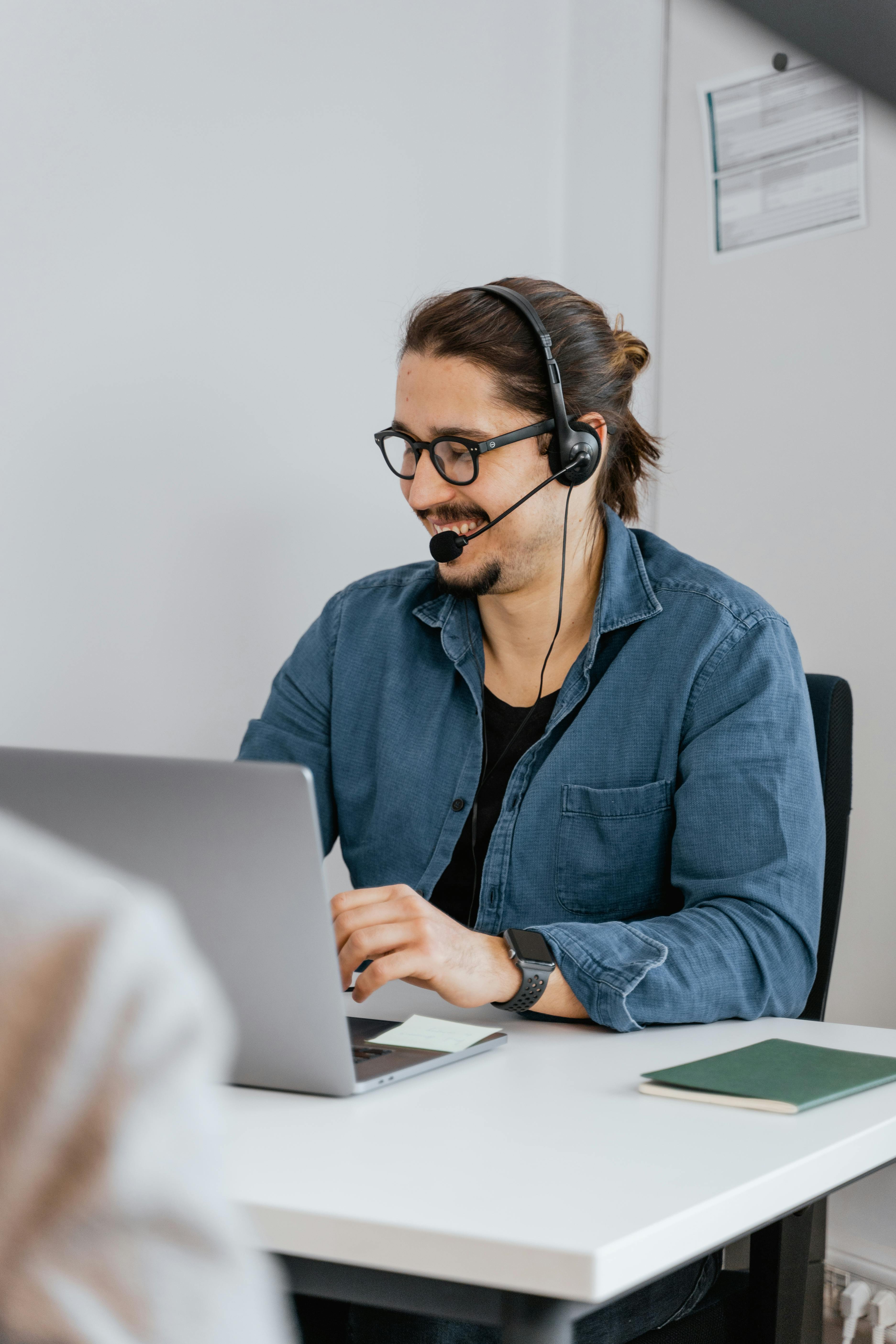 man with black headset and mouthpiece sitting at table