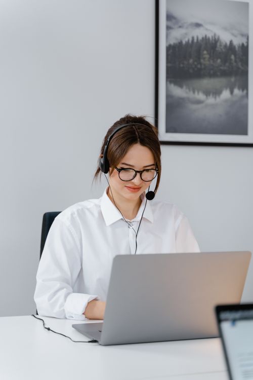 Free Professional woman providing customer support using a laptop and headset in a modern office. Stock Photo