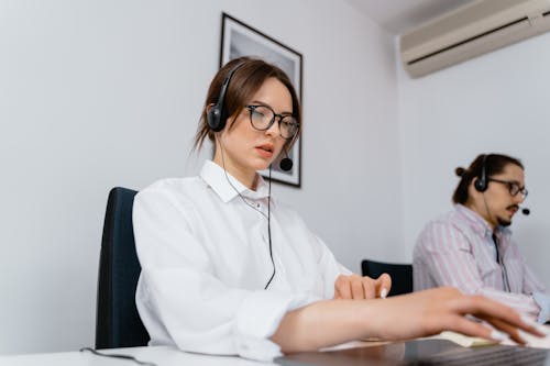 Low-Angle Shot of a Woman in a White Shirt Wearing a Black Headset